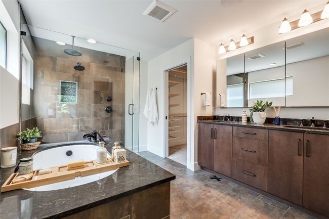 The built-in jetted tub is surrounded by a granite ledge and tile backsplash and comes with a retractable shower wand. | Image 25