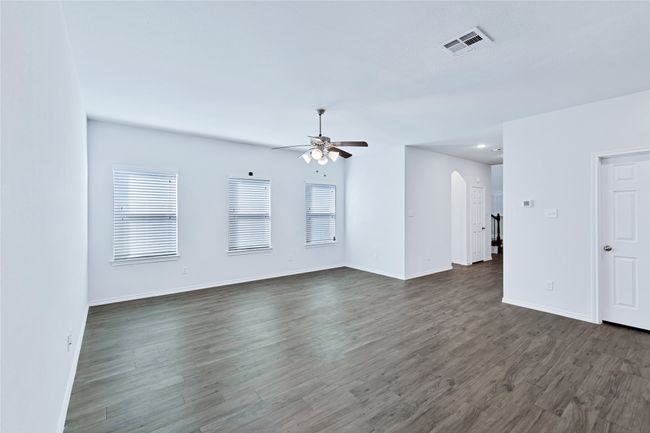 Unfurnished living room with ceiling fan, arched walkways, and dark wood-style flooring | Image 4