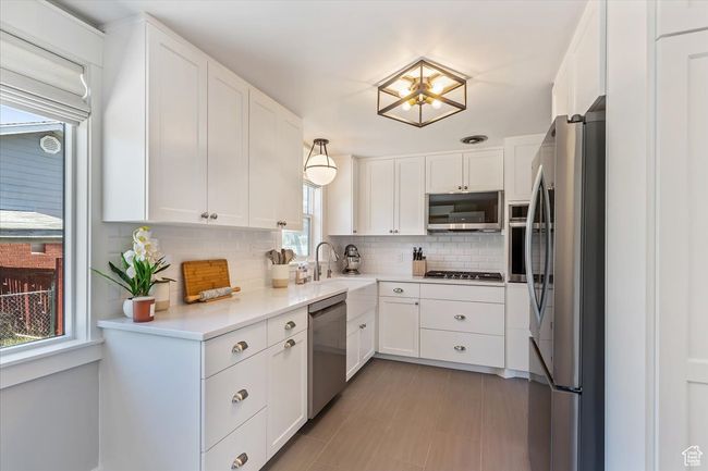 Kitchen featuring stainless steel appliances, backsplash, and white cabinetry | Image 18