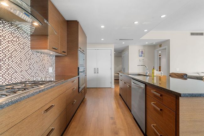 Kitchen featuring appliances with stainless steel finishes, modern cabinets, brown cabinetry, range hood, and recessed lighting | Image 15