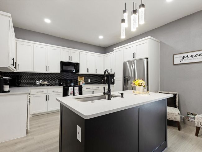 Kitchen with black appliances, a sink, light wood-style flooring, backsplash, and pendant lighting | Image 18