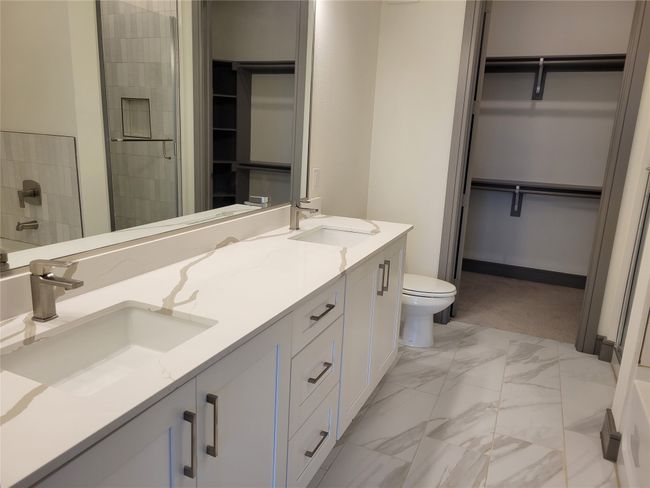 Full bath with a spacious closet, marble look tiles, double vanity, and a shower stall | Image 12