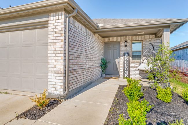 Property entrance with a shingled roof, a garage, and brick siding | Image 23