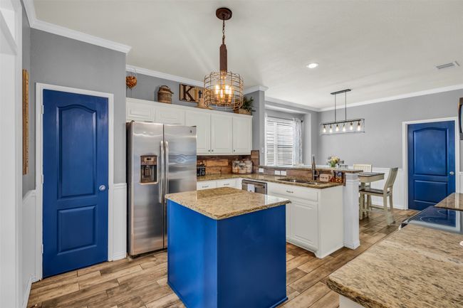 Kitchen featuring appliances with stainless steel finishes, a kitchen island, white cabinets, and pendant lighting | Image 13