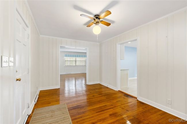 Unfurnished room featuring baseboards, hardwood / wood-style flooring, ceiling fan, and crown molding | Image 12