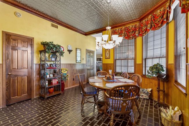 Dining space featuring wooden walls, ornamental molding, and a chandelier | Image 15