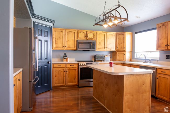 Kitchen with stainless steel appliances, a sink, lofted ceiling, light countertops, and wood flooring | Image 8