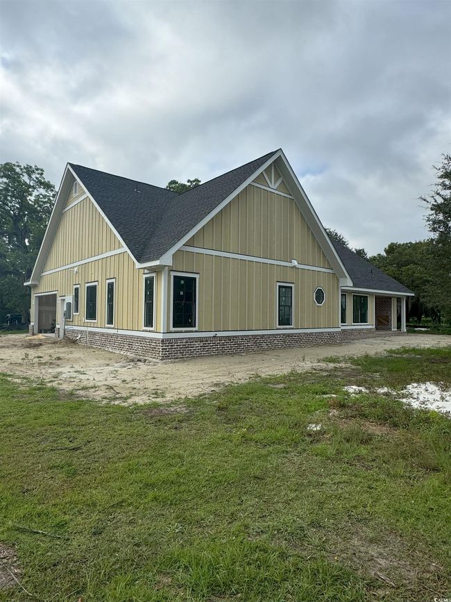 View of front facade with board and batten siding, a shingled roof, and a front yard | Image 6