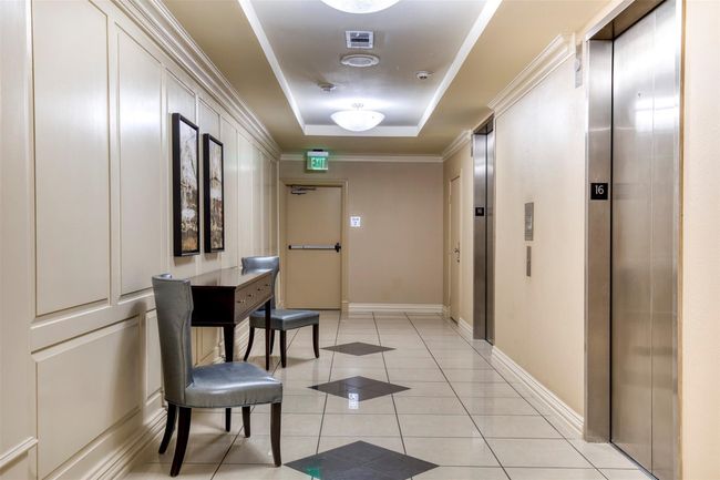 Hallway with elevator, crown molding, a tray ceiling, and light tile patterned floors | Image 32