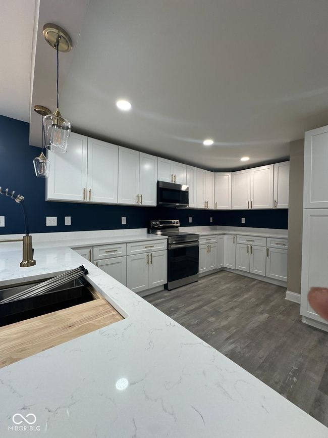 Unit 2 - kitchen featuring stainless steel appliances, dark wood-style floors, white cabinets, light stone countertops, and recessed lighting | Image 17
