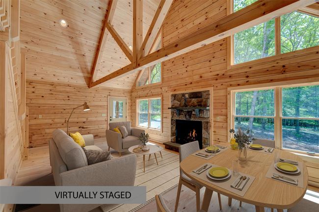 Living room with wood finished floors, high vaulted ceiling, wooden walls, a stone fireplace, and a wood ceiling with exposed beams | Image 4