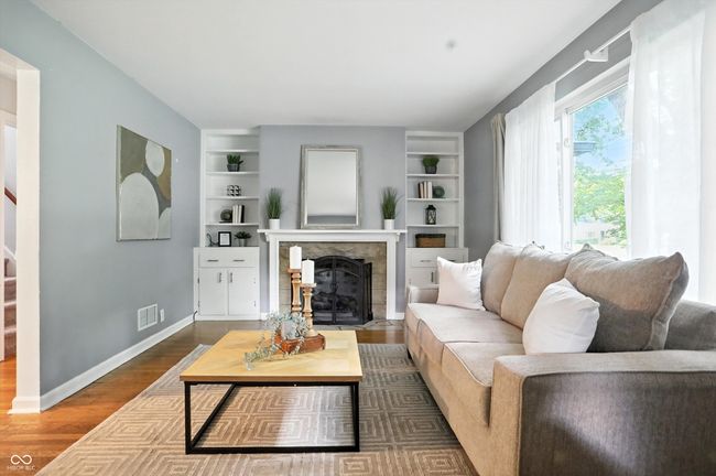 living room featuring dark wood-style flooring, a fireplace with flush hearth, and built in features | Image 17