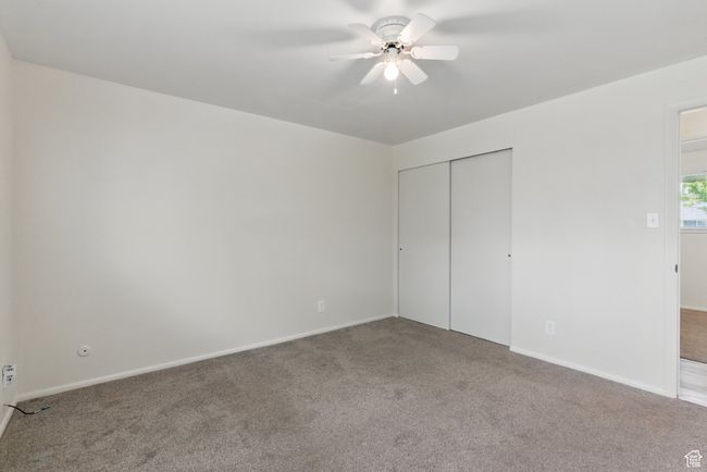 Unfurnished bedroom featuring a ceiling fan, baseboards, a closet, and carpet | Image 13