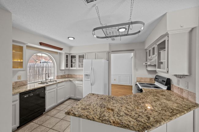 Kitchen featuring white appliances, a sink, under cabinet range hood, a peninsula, and light stone countertops | Image 15