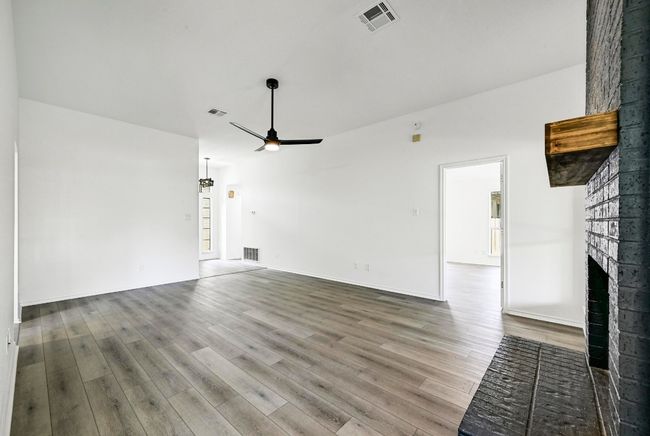 Unfurnished living room featuring a fireplace, a ceiling fan, and wood finished floors | Image 10