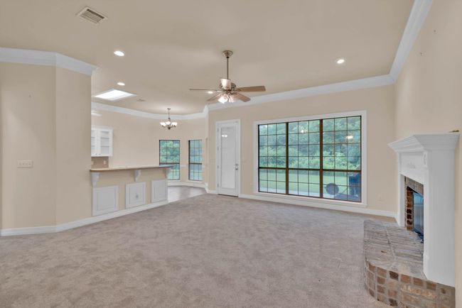 Unfurnished living room with crown molding, carpet, a fireplace, ceiling fan, and a chandelier | Image 5