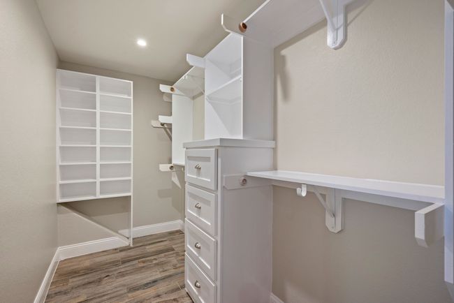Custom built-ins in this primary walk-in closet maximize organization and storage with drawers, shelves, and plenty of hanging space. | Image 28