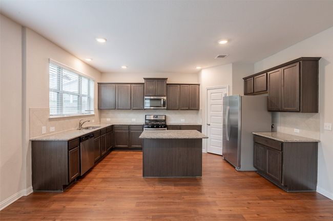 Kitchen featuring visible vents, tasteful backsplash, dark brown cabinets, a sink, and stainless steel appliances | Image 4