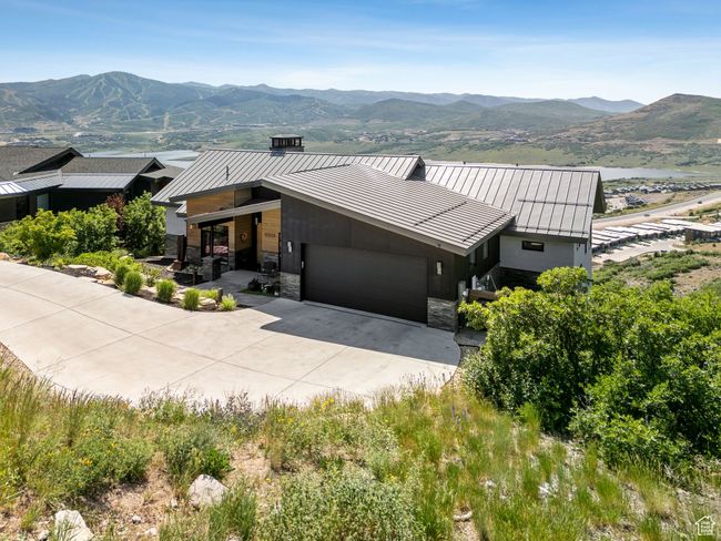 View of front of house with a standing seam roof, a garage, a mountain view, driveway, and a metal roof | Image 6
