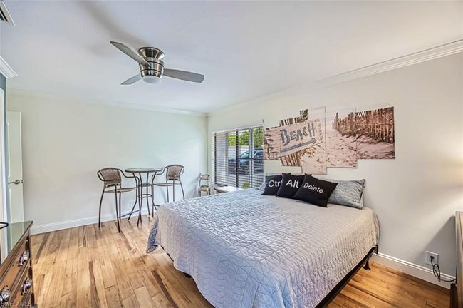 Bedroom featuring visible vents, baseboards, ornamental molding, wood finished floors, and a ceiling fan | Image 38