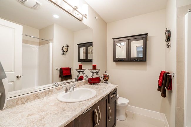 Bathroom with vanity, toilet, a shower, tile patterned flooring, and baseboards | Image 24