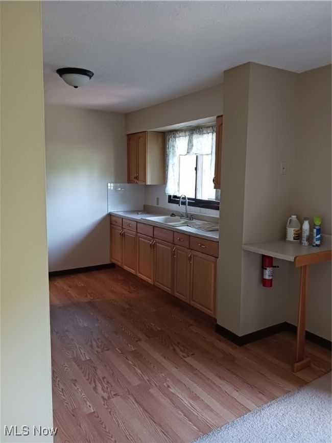 Kitchen with dark wood-style flooring, light countertops, and light brown cabinets | Image 5