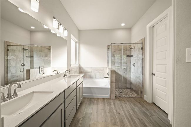 Modern finishes in this spa-inspired primary bath with wood-look tile and custom tiling. | Image 20