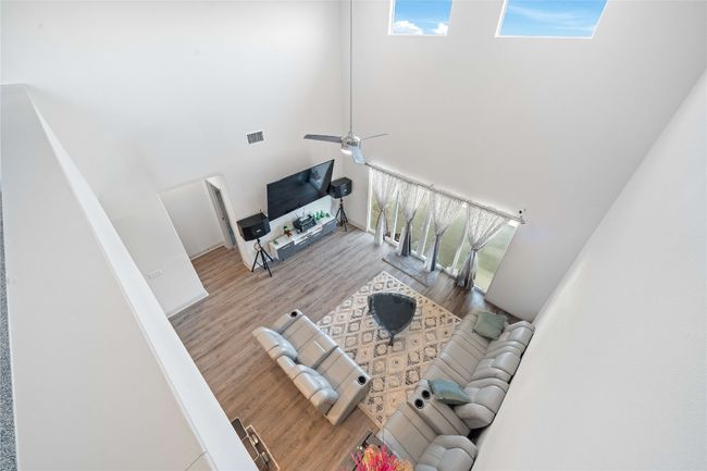 Living room with ceiling fan, visible vents, a high ceiling, and wood finished floors | Image 17