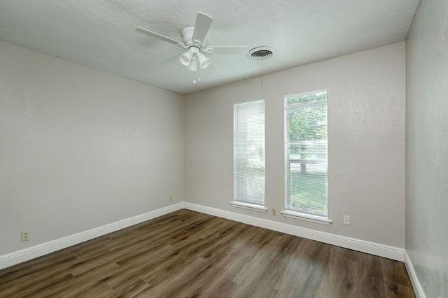 Empty room with dark wood finished floors and ceiling fan | Image 9