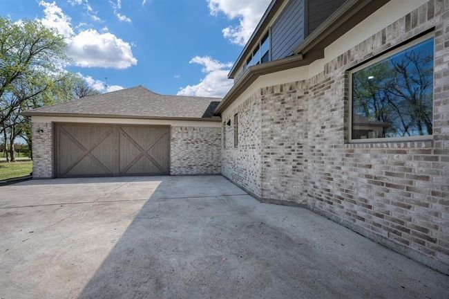 View of property exterior with brick siding, concrete driveway, and an attached garage | Image 33