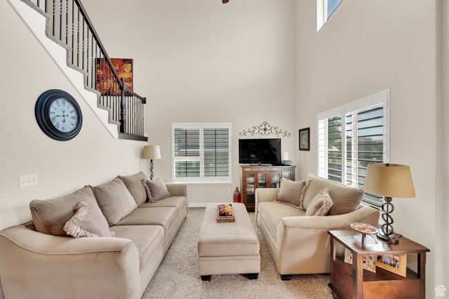Carpeted living room with a high ceiling and stairway | Image 10
