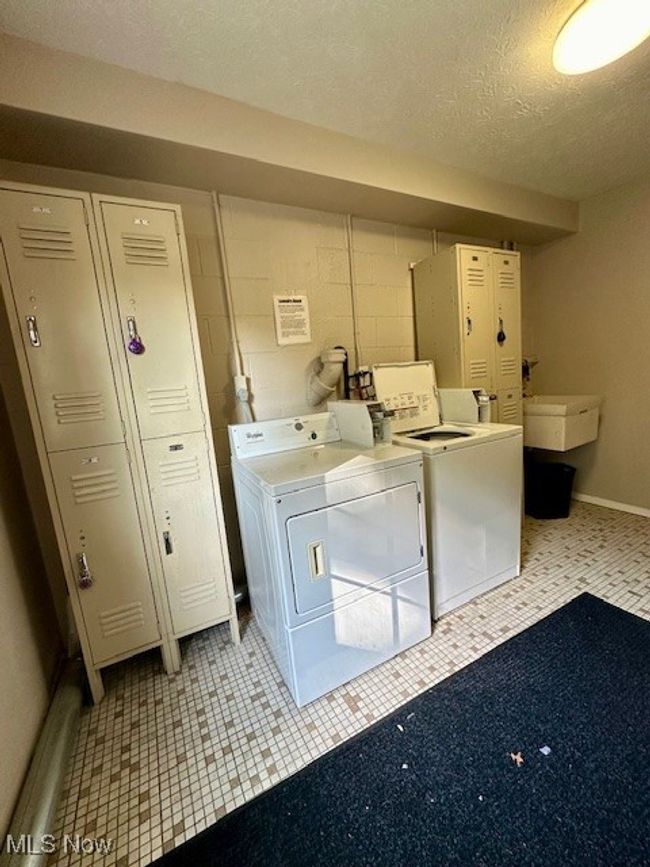 Clothes washing area featuring a textured ceiling, sink, and independent washer and dryer | Image 19
