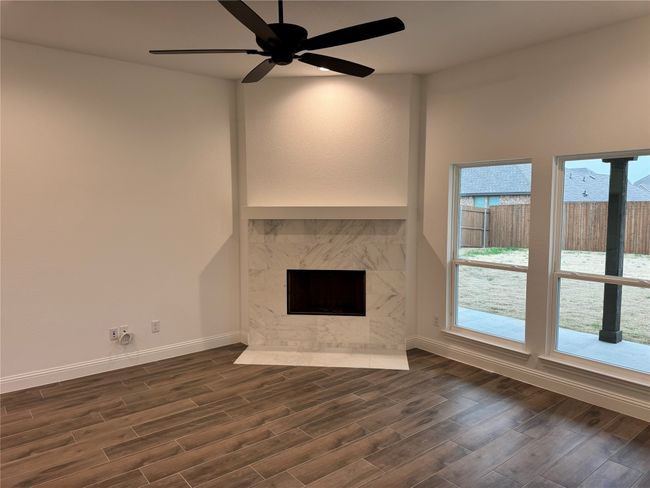 Unfurnished living room featuring dark hardwood / wood-style flooring, a fireplace, and ceiling fan | Image 5