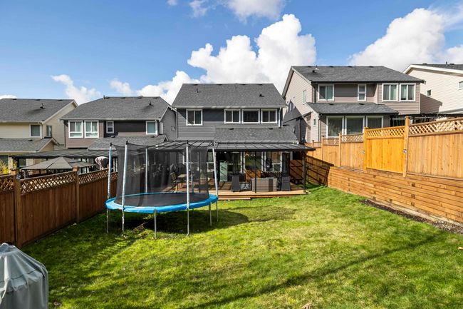Back of property with a fenced backyard, a residential view, a lawn, and a trampoline | Image 36