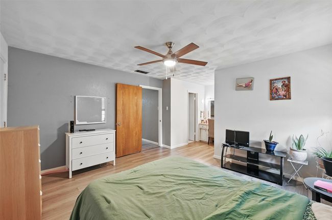 Bedroom featuring wood finished floors, baseboards, ensuite bath, and a ceiling fan | Image 25