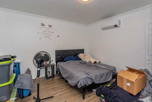 Bedroom with crown molding, light wood-style floors, and a wall mounted air conditioner | Image 21