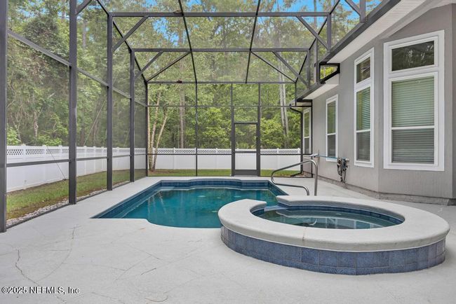 Screened-in saltwater pool/heated spa with plenty of space for seating and covered dining | Image 36