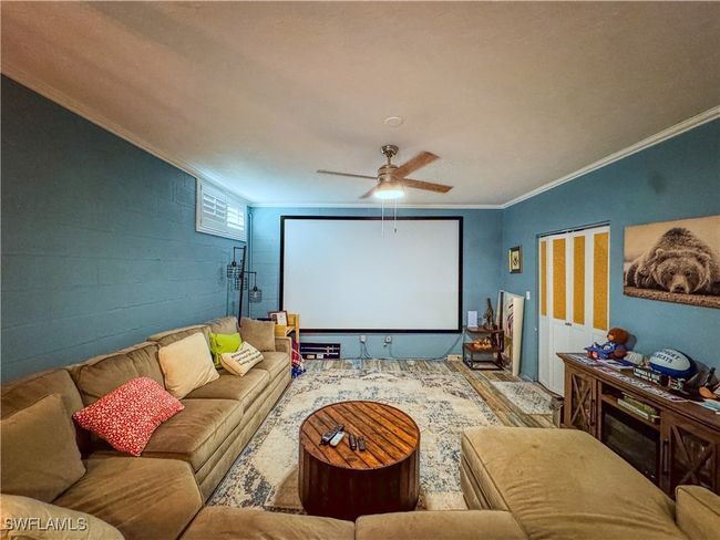 Home theater with concrete block wall, ceiling fan, wood finished floors, and ornamental molding | Image 19