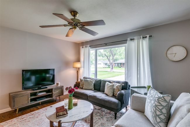Living room featuring wood floors grand picture window, and ceiling fan | Image 5