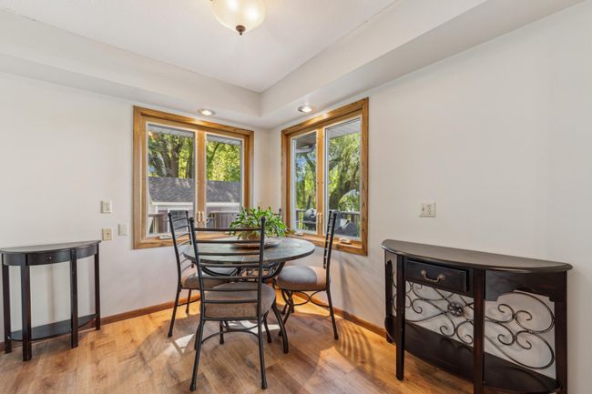 Cozy informal dining area surrounded by windows, offering a perfect spot for morning coffee with serene outdoor views. | Image 12