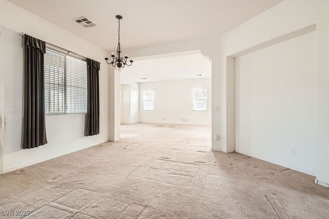 Empty room with visible vents, an inviting chandelier, and carpet floors | Image 7