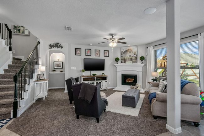 Living room with arched walkways, ceiling fan, stairway, carpet, and a textured ceiling | Image 8