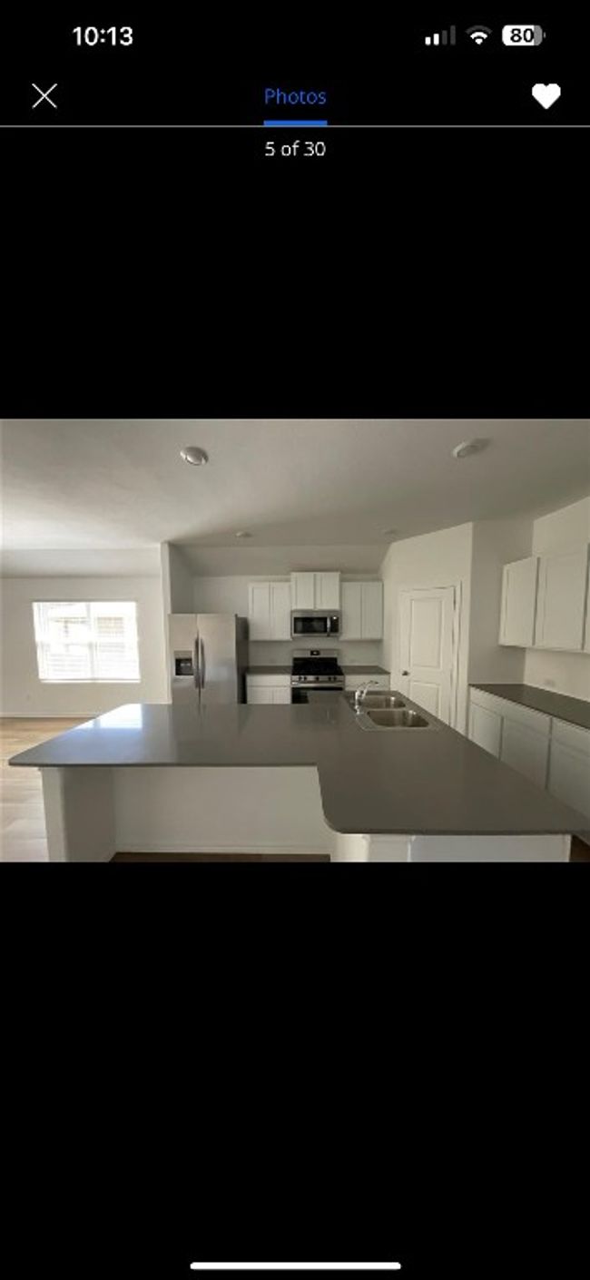 Kitchen featuring appliances with stainless steel finishes, white cabinets, a sink, and a spacious island | Image 5