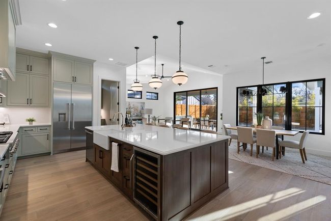Kitchen featuring beverage cooler, stainless steel built in refrigerator, light wood-type flooring, light countertops, and vaulted ceiling | Image 14