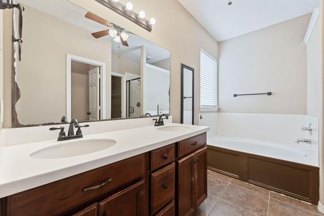 Primary bath includes double vanities, separate tub and shower, and ceiling fan | Image 25