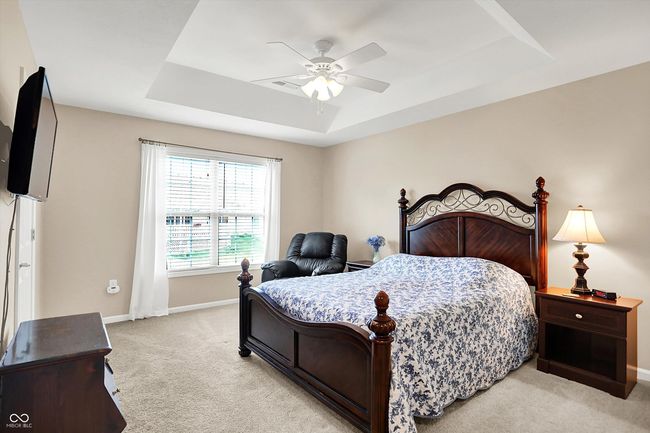 Master bedroom featuring a raised ceiling, light carpet, baseboards, and ceiling fan | Image 21