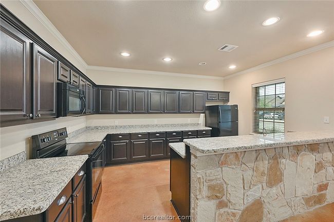 Kitchen with crown molding, light stone counters, black appliances, visible vents, and recessed lighting | Image 5