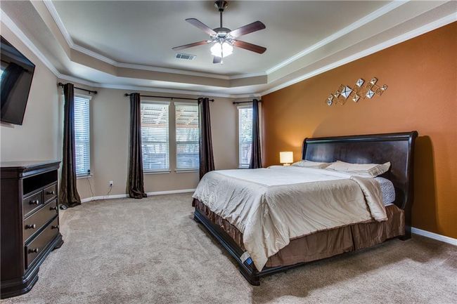 Bedroom with a tray ceiling, carpet floors, ornamental molding, and ceiling fan | Image 13