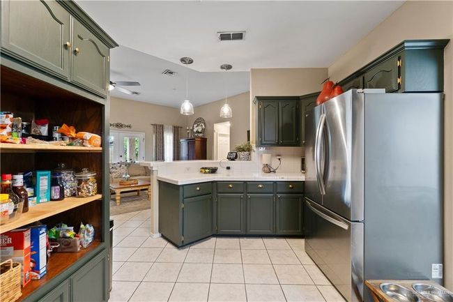 Kitchen featuring freestanding refrigerator, a peninsula, green cabinetry, and a ceiling fan | Image 16