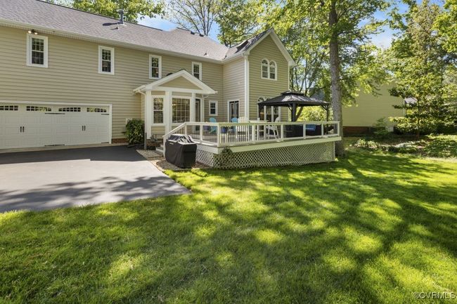 Back of house with a gazebo, a deck, a garage, a yard, and roof with shingles | Image 7